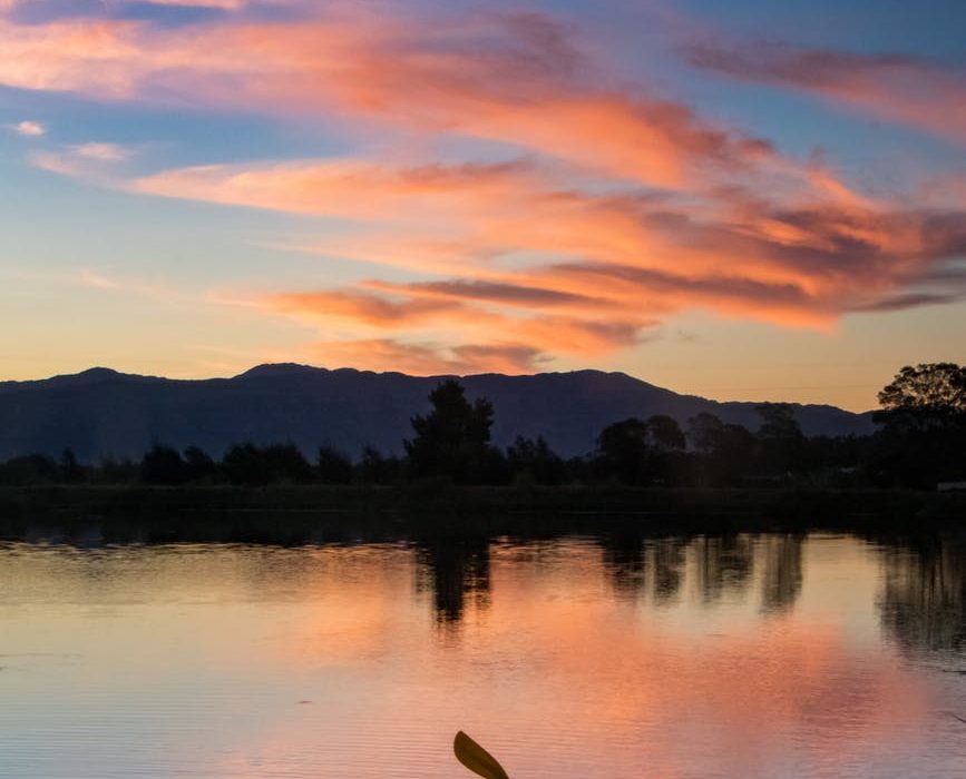 photo of person riding kayak during dawn